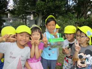 幼児クラスは、合同で近隣の公園へ散歩に行きました。 コオロギやバッタを捕まえて笑顔でピースサインの5歳児さん達。